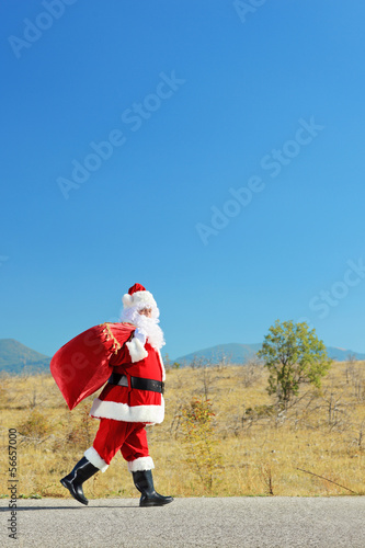 Santa claus with bag walking on an open road