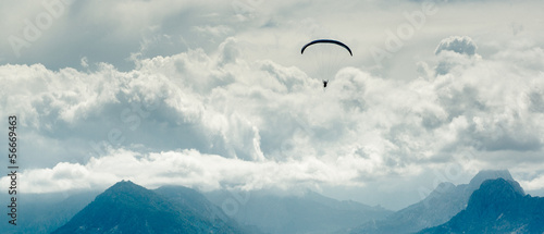 Paraglider over mountains and cloudy sky background