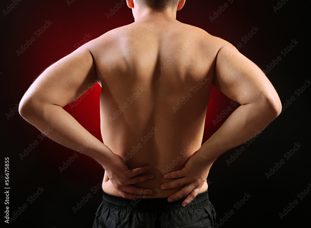 Fototapeta premium Young man with back pain, on red background