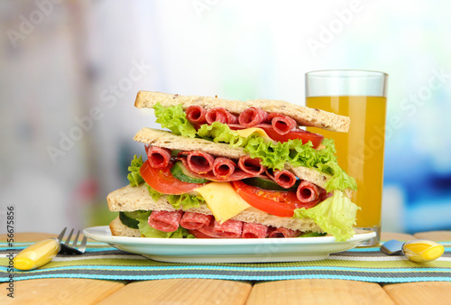 Huge sandwich on wooden table, on bright background