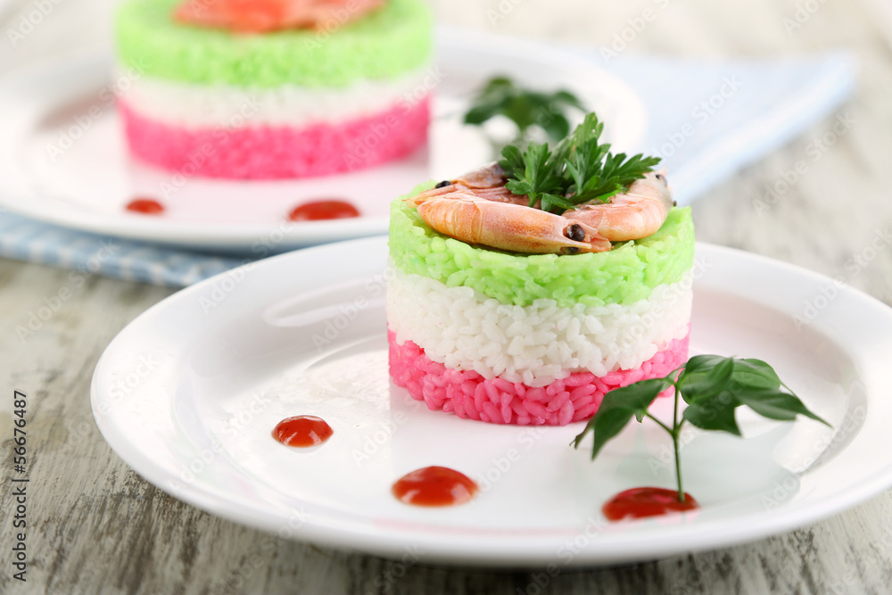 Colored rice on plates on napkin on wooden table Colored rice on plates on napkin on wooden table