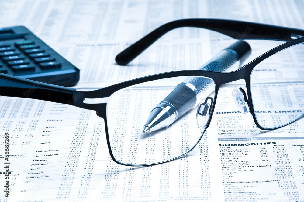 glasses near calculator with pen on financial newspaper glasses near calculator with pen on financial newspaper