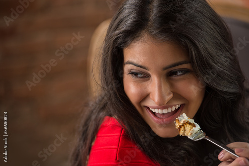Young hispanic girl eating cake in the cafe