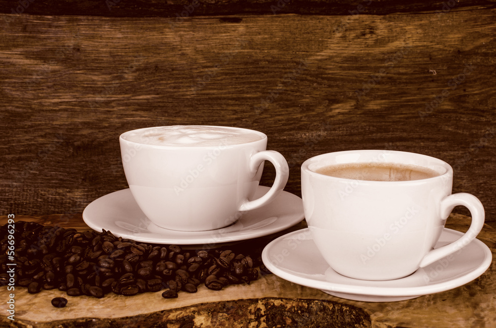 Kaffeetassen und Kaffeebohnen vor altem Holz-Hintergrund Kaffeetassen und Kaffeebohnen vor altem Holz-Hintergrund