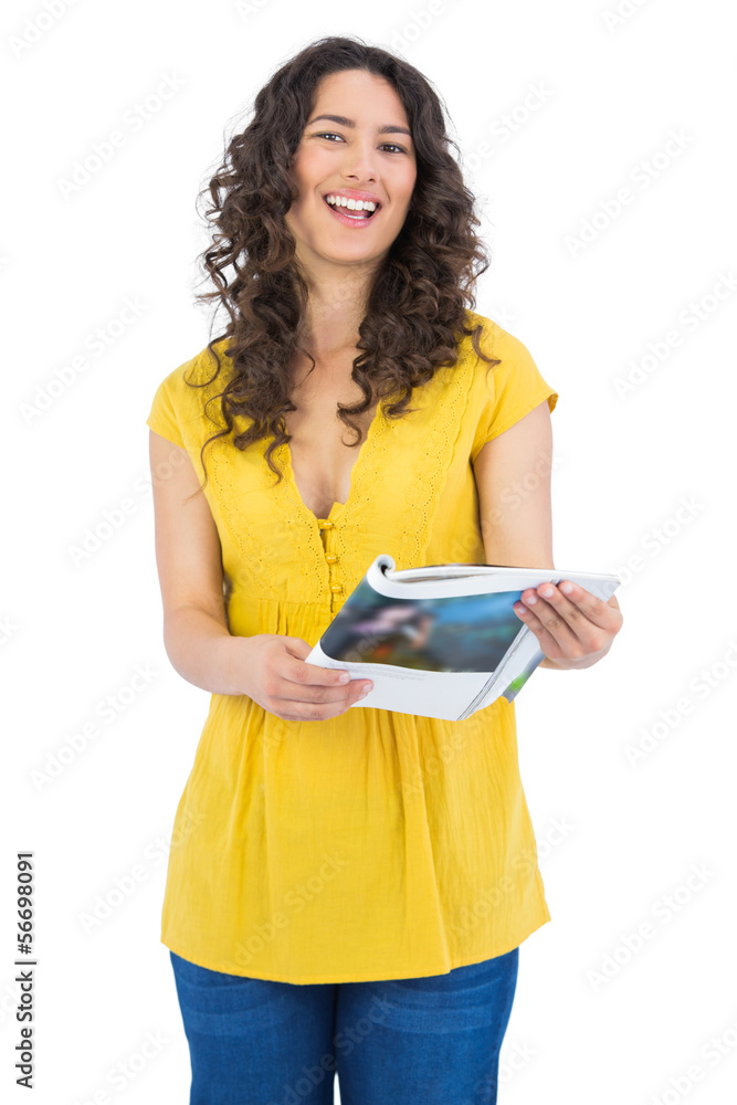 Curly haired brunette laughing while reading magazine Curly haired brunette laughing while reading magazine