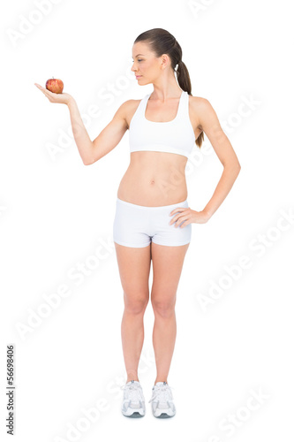 Fit woman in sportswear holding red apple
