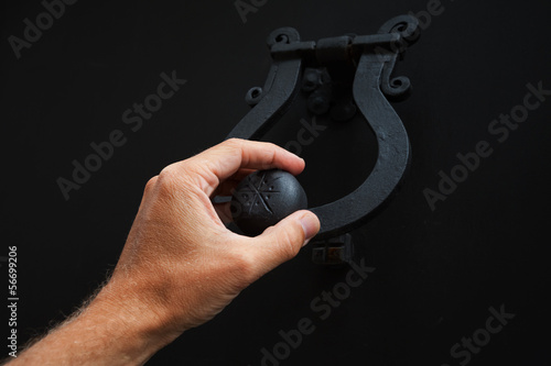 Male hand knocking old black metal door