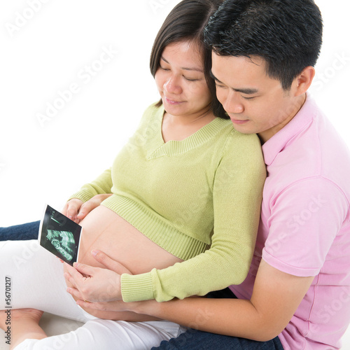 Pregnant couple looking at ultrasound scan photo