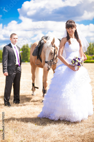 Beautiful bride and handsome groom posing with horse
