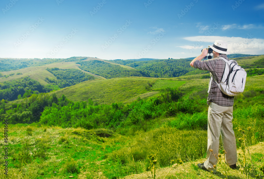 Explorer watching beautiful landscape through binoculars