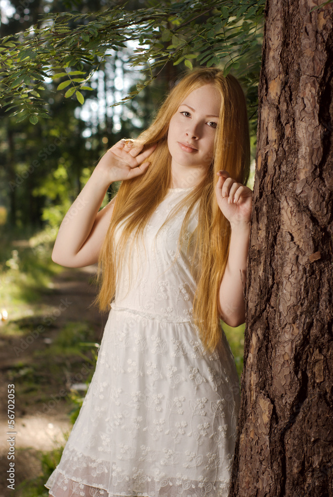 A young girl with long blond hair, standing in the forest A young girl with long blond hair, standing in the forest