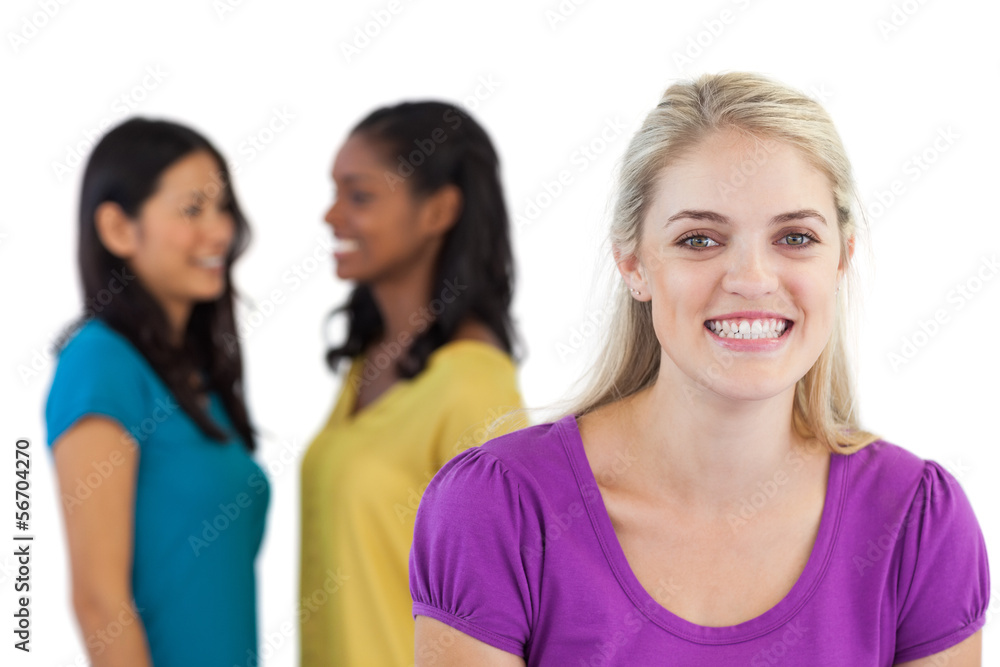 Smiling blonde woman looking at camera with two women behind her Smiling blonde woman looking at camera with two women behind her
