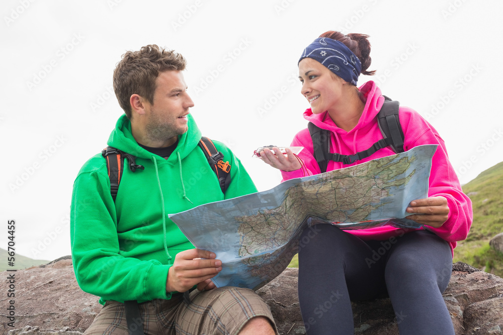 Couple using map and compass sitting on a rock stock photo adobe stock