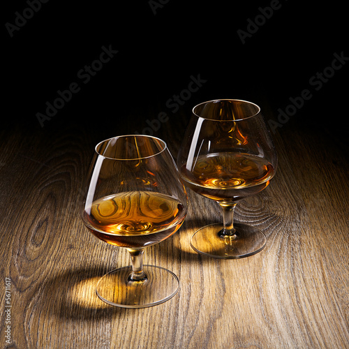 Two goblets of brandy warmed by the glow of the lights on wooden