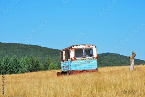 Rusty trailer on an yellow field background