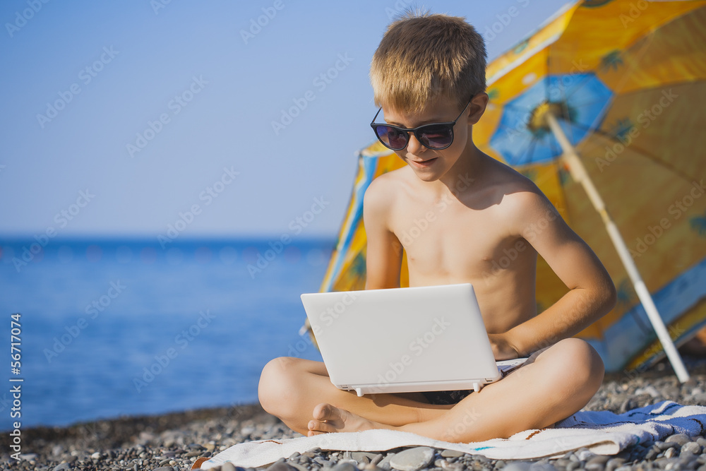 happy smiling kid with laptop on a beach