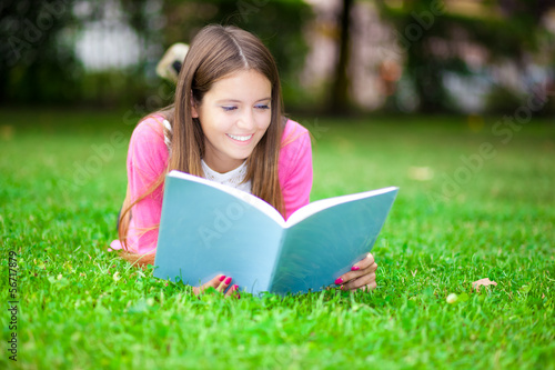 Young female student reading a book on the grass