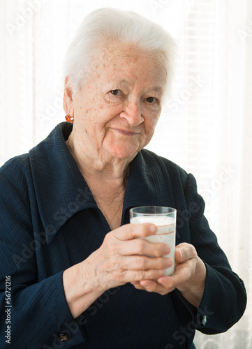 Old woman holding a glass milk