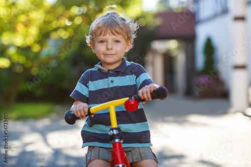 Little toddler boy riding on his bicycle in summer.