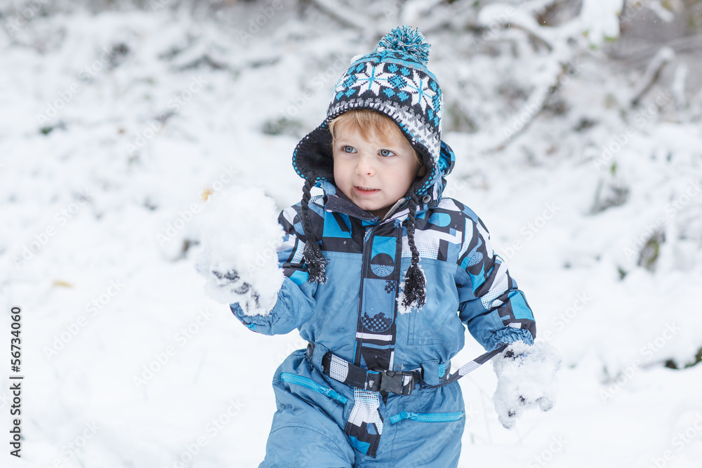 Adorable toddler boy having fun with snow on winter day Adorable toddler boy having fun with snow on winter day