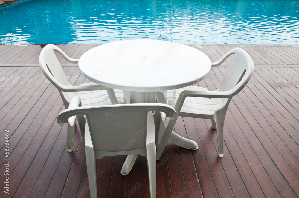 chairs and tables next to a swimming pool chairs and tables next to a swimming pool