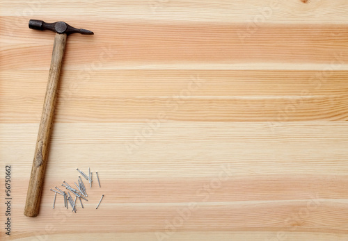 Hammer and metal panel pins on a woodgrain background