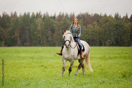 A girl rides a horse on the field