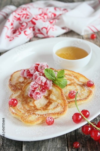 Pancakes with red currant and honey on wooden background