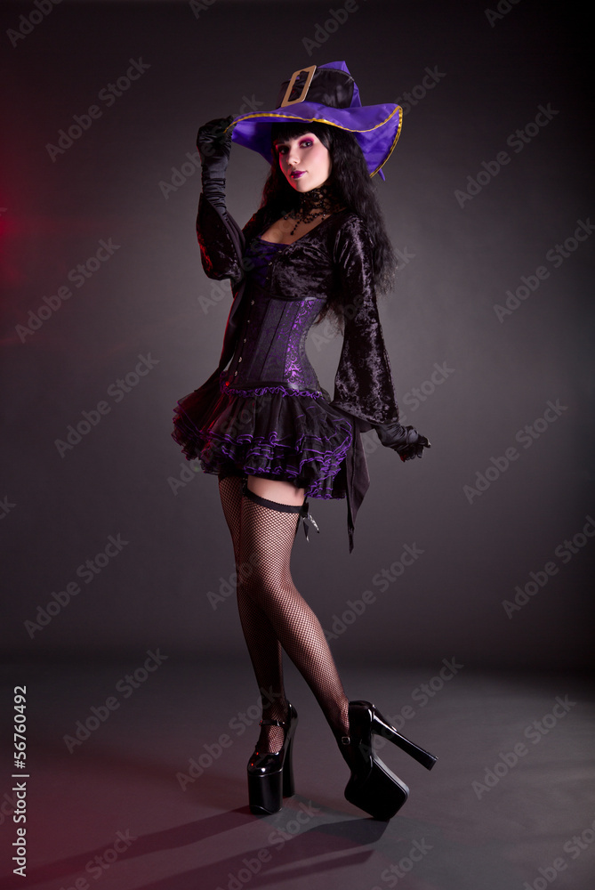 Pretty witch in purple and black gothic Halloween costume