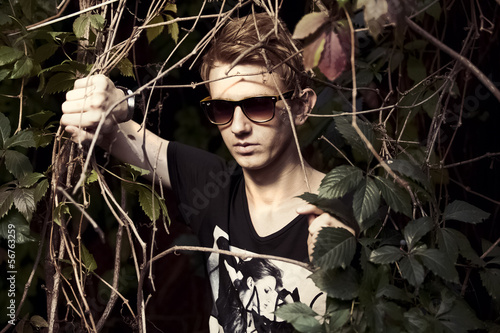 Handsome man in sunglasses ripping bushes photo