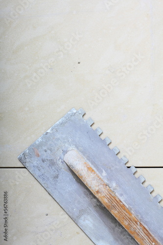 building work tool dirty trowel on new tile floor surface photo