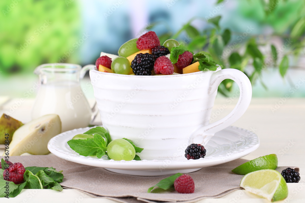 Fruit salad in cup on wooden table on nature background Fruit salad in cup on wooden table on nature background