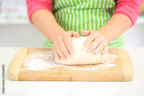 Female hands in flour closeup kneading dough on table