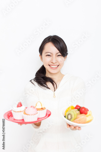 カップケーキと果物を持った女性