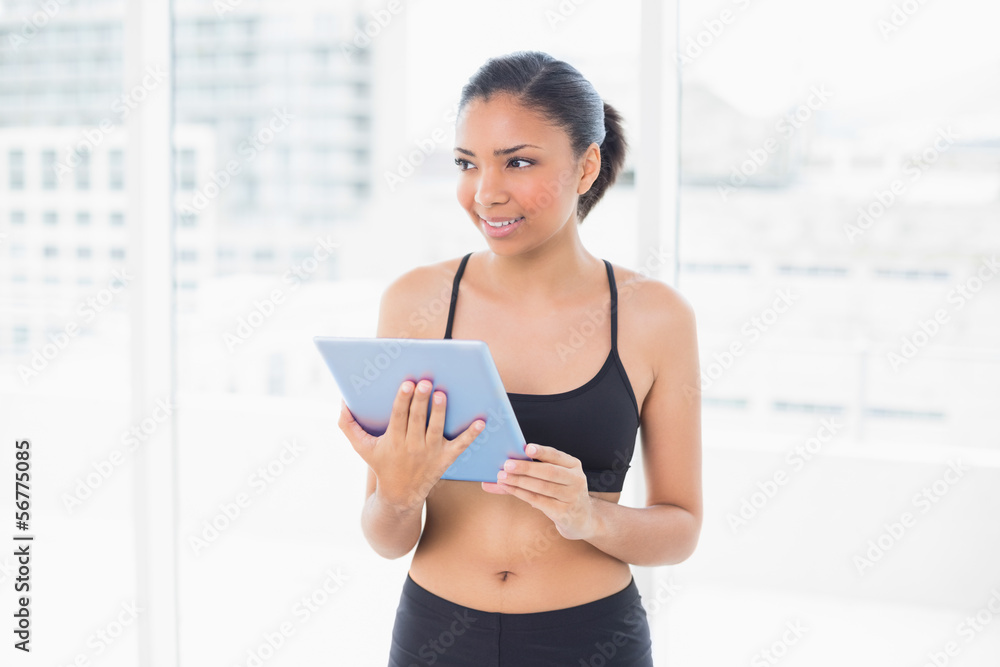 Thinking dark haired model in sportswear holding a tablet pc Thinking dark haired model in sportswear holding a tablet pc