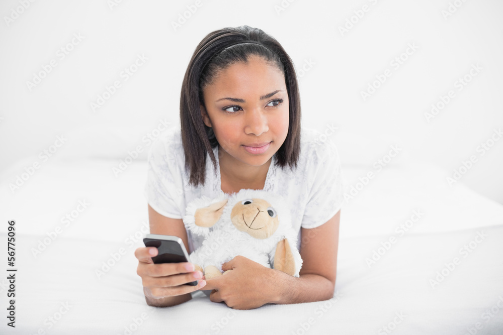 Thoughtful young dark haired model holding a mobile phone and a Thoughtful young dark haired model holding a mobile phone and a