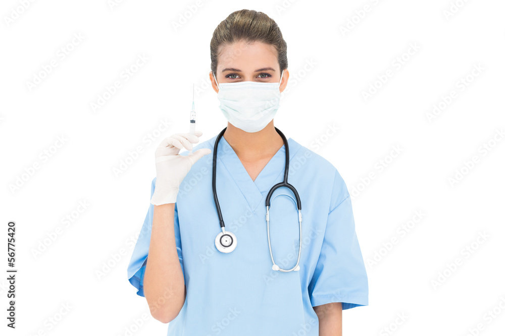 Cute brown haired nurse in blue scrubs wearing a protective mask