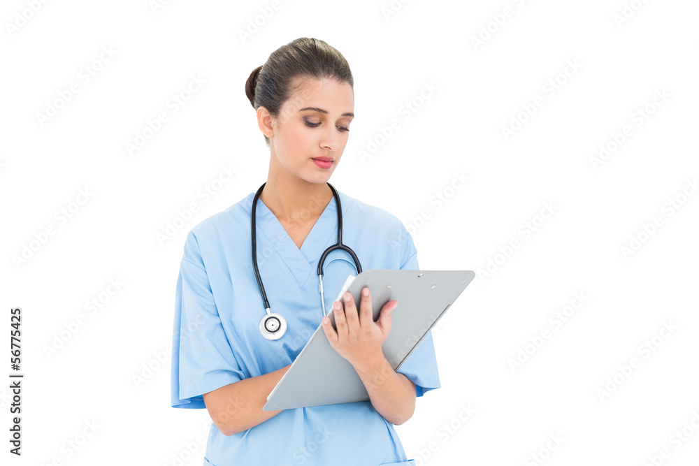 Cute brown haired nurse in blue scrubs checking a report Cute brown haired nurse in blue scrubs checking a report