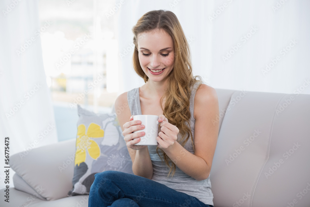 Content young woman sitting on sofa holding mug Content young woman sitting on sofa holding mug