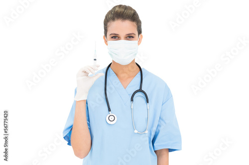 Cute brown haired nurse in blue scrubs wearing a protective mask
