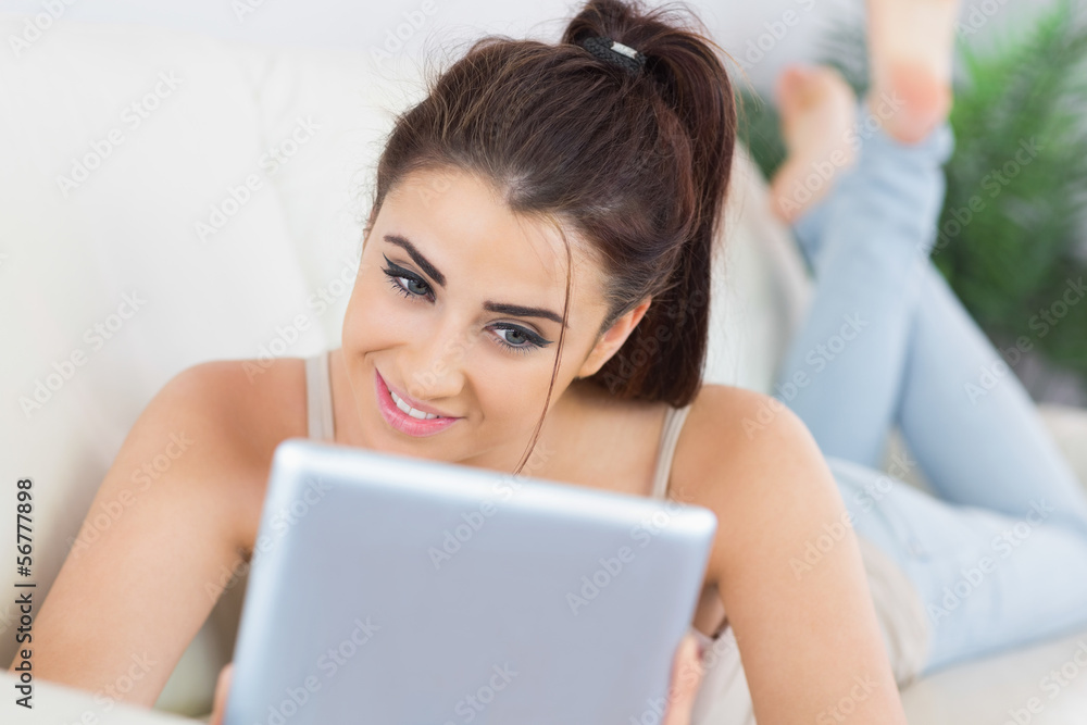 Pretty casual woman using her tablet lying on a couch Pretty casual woman using her tablet lying on a couch