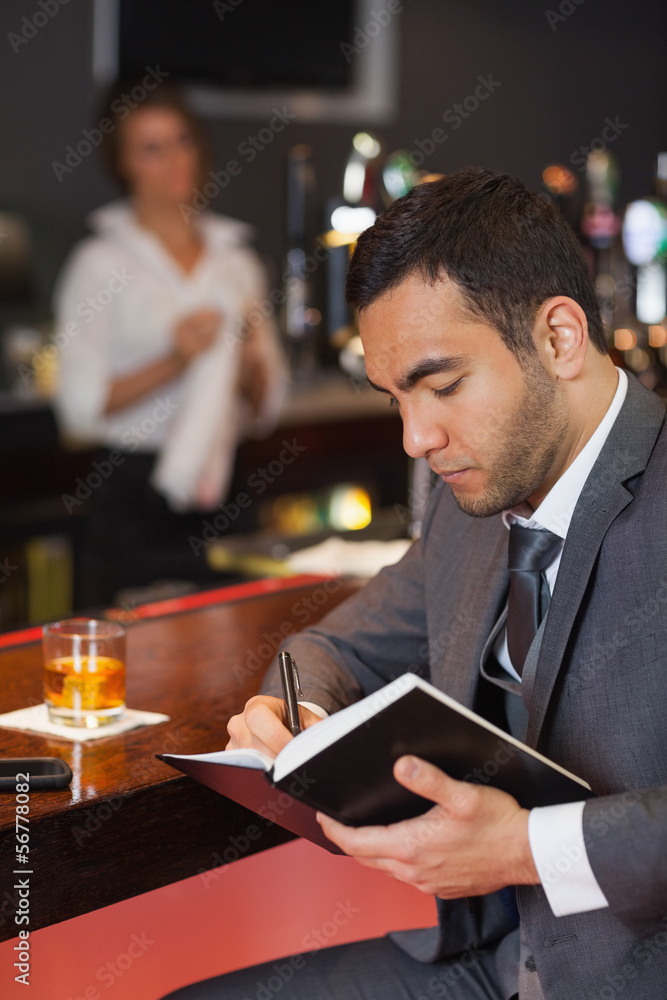 Obraz premium Cheerful businessman writing on his datebook