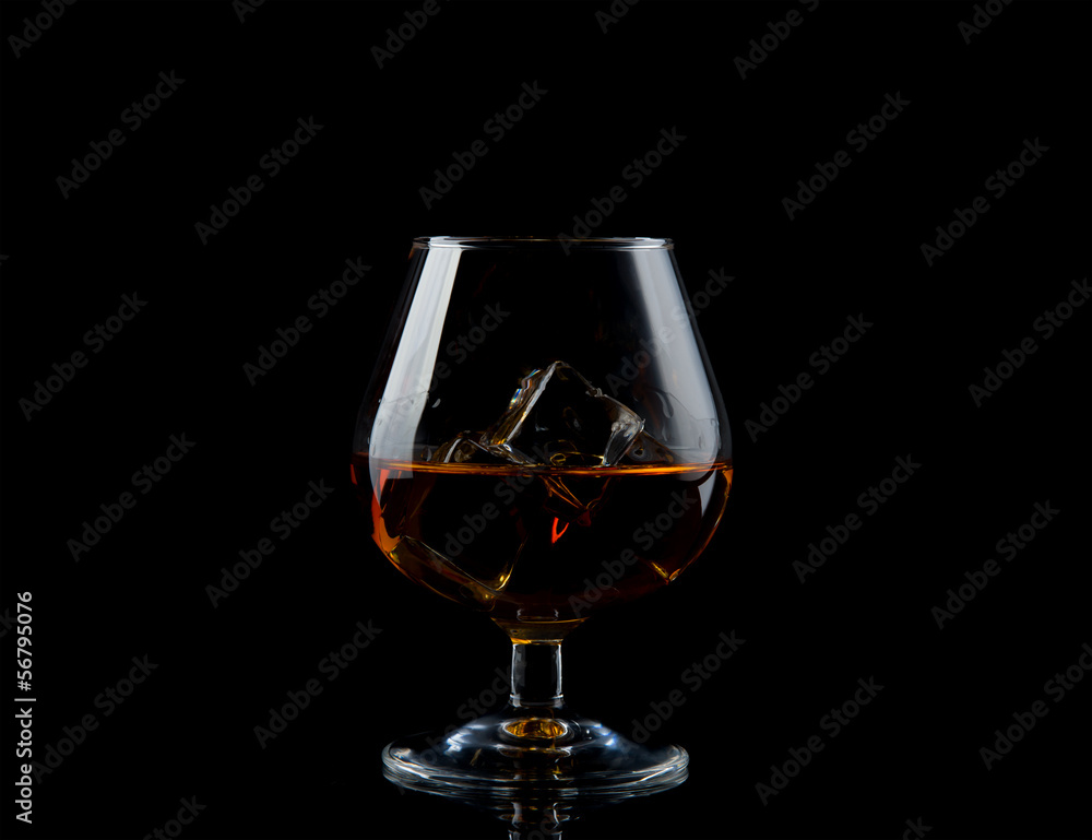 Glass of whiskey with ice on black Glass of whiskey with ice on black