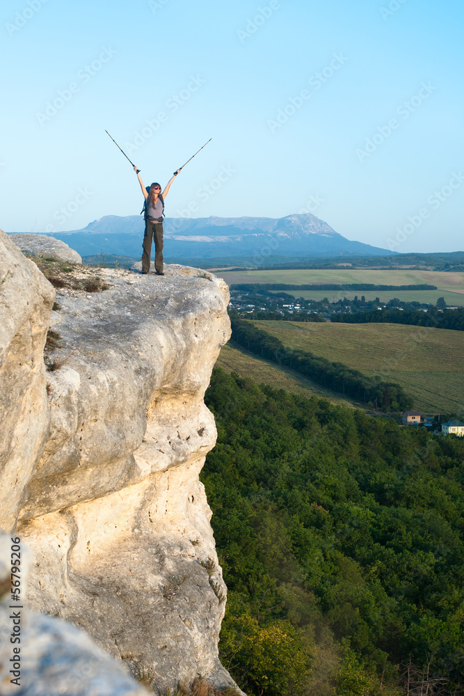 Obraz premium Smiling young woman standing on the top of mountain