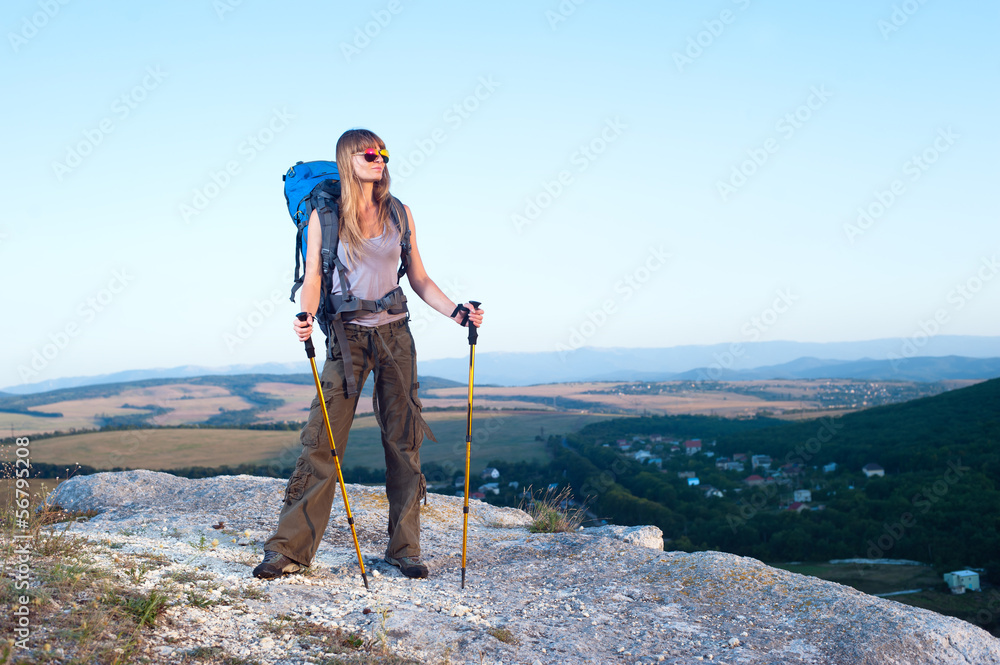 Smiling young woman standing on the top of mountain