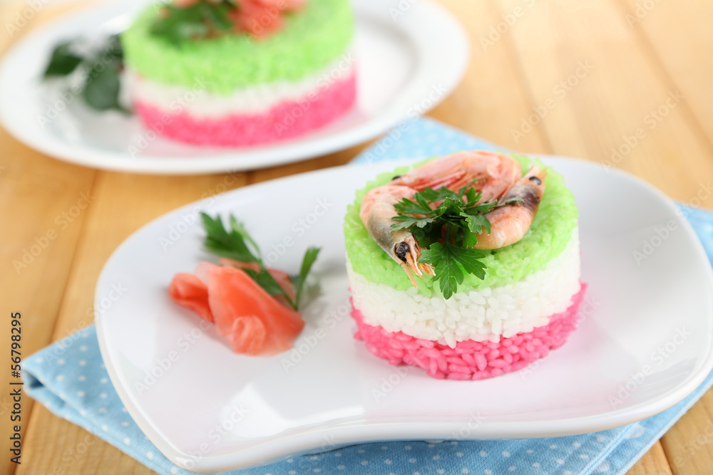 Colored rice on plates on napkin on wooden table Colored rice on plates on napkin on wooden table
