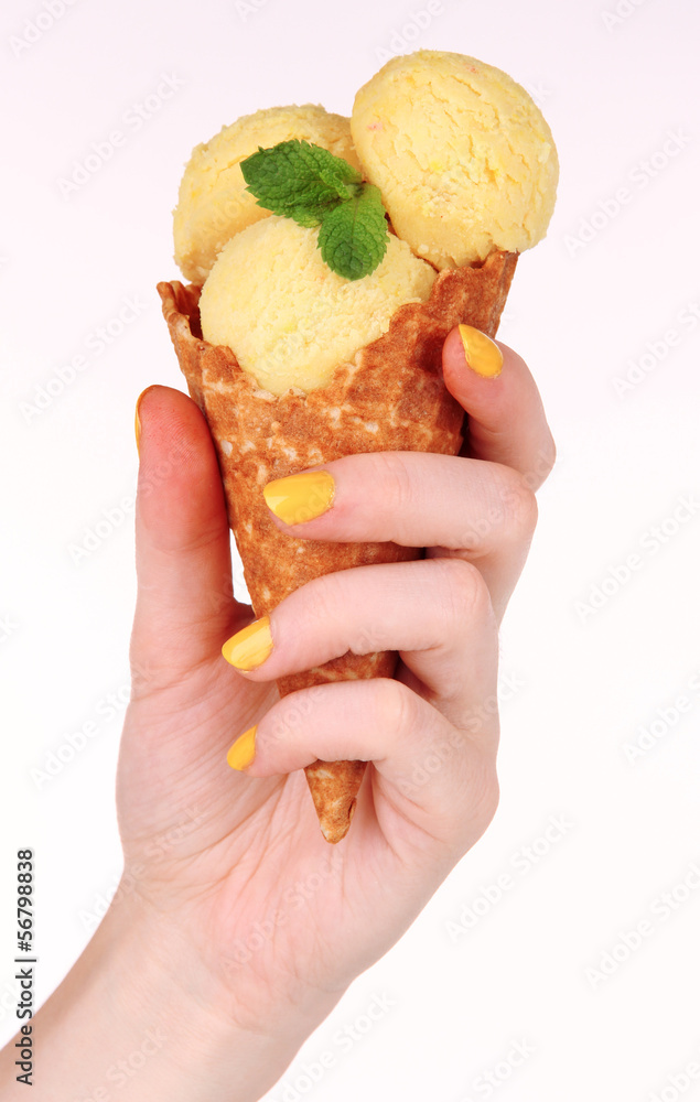Hand holding yellow ice cream with mint in waffle cone Hand holding yellow ice cream with mint in waffle cone