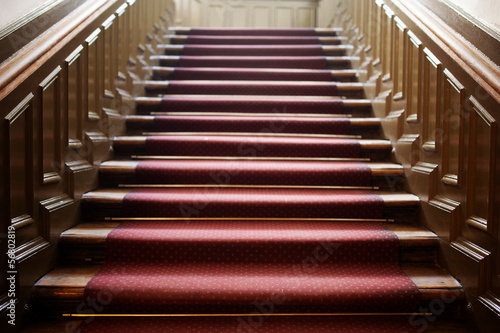 Empty wooden staircase with red carpet