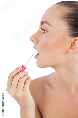 Profile of woman putting lip gloss on her lips