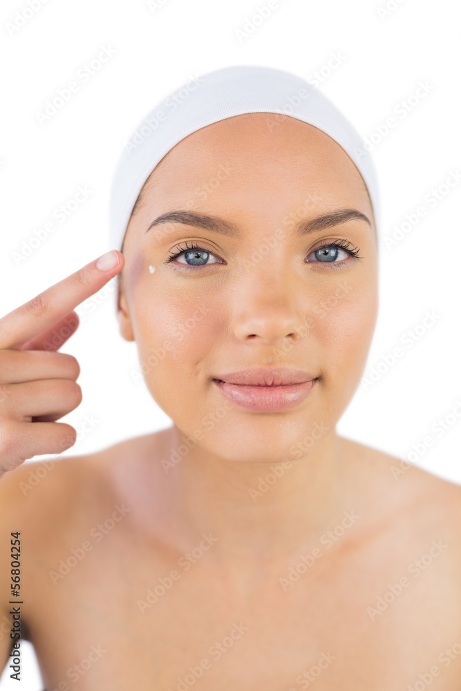 Attractive woman weaing headband putting cream on her face Attractive woman weaing headband putting cream on her face